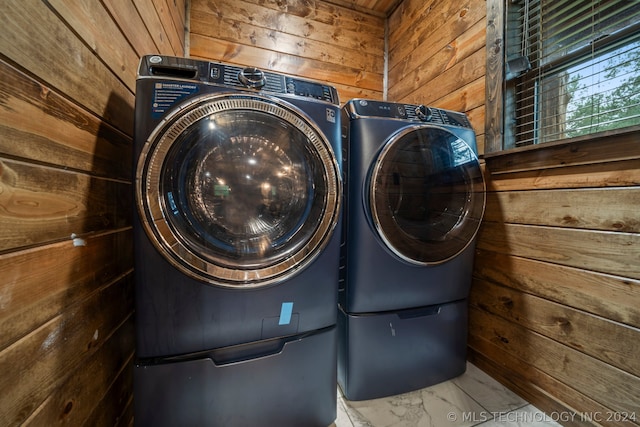 laundry room with washer and dryer and wooden walls