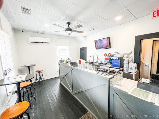 home office featuring dark hardwood / wood-style floors, ceiling fan, a paneled ceiling, and a wall mounted air conditioner