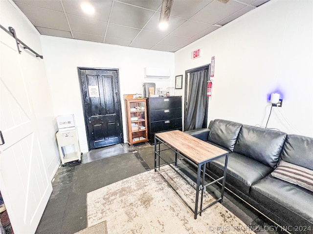 living room with a barn door and a drop ceiling