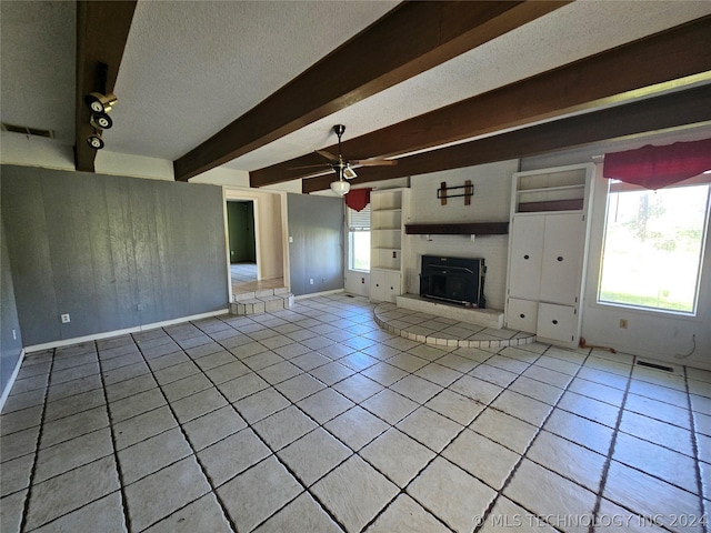 unfurnished living room with a textured ceiling, ceiling fan, beam ceiling, light tile patterned floors, and built in features