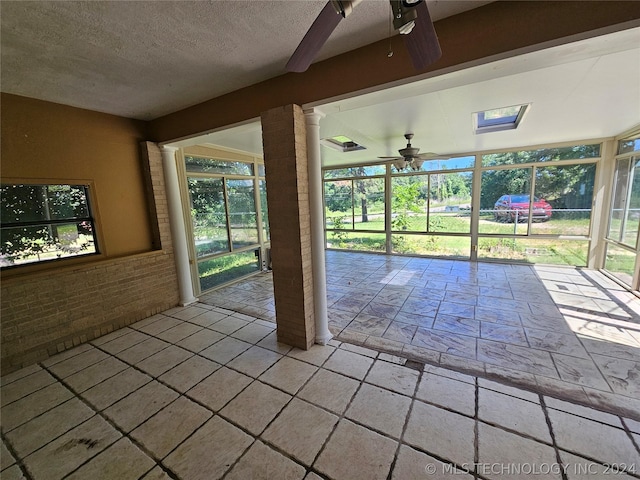 unfurnished sunroom with ceiling fan and a skylight