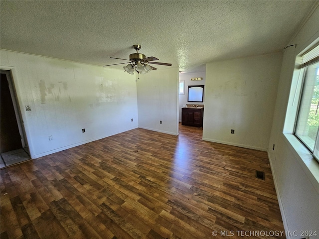 unfurnished living room featuring ceiling fan, dark hardwood / wood-style flooring, and a textured ceiling