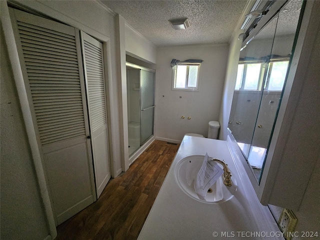 bathroom featuring a textured ceiling, toilet, vanity, a shower with shower door, and hardwood / wood-style flooring