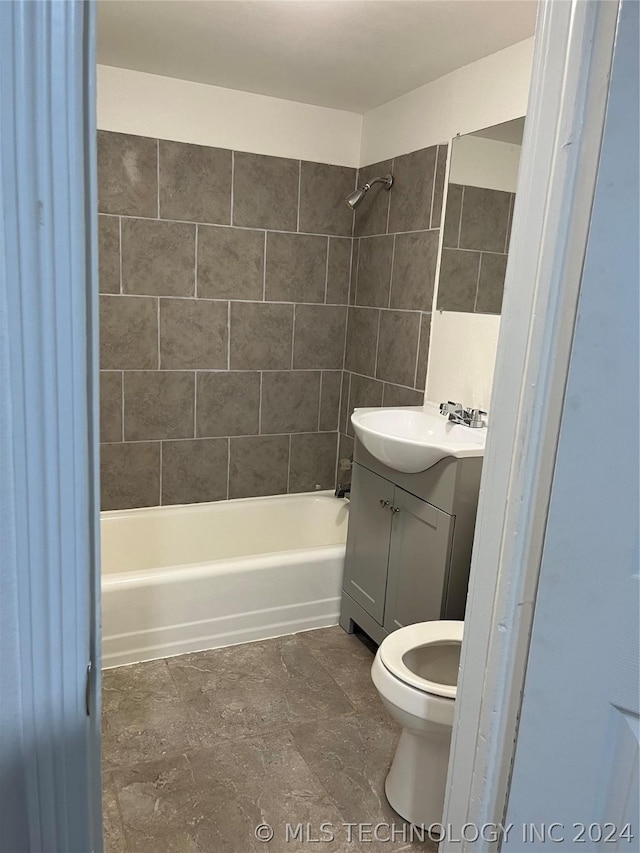 full bathroom featuring vanity, tiled shower / bath combo, and toilet