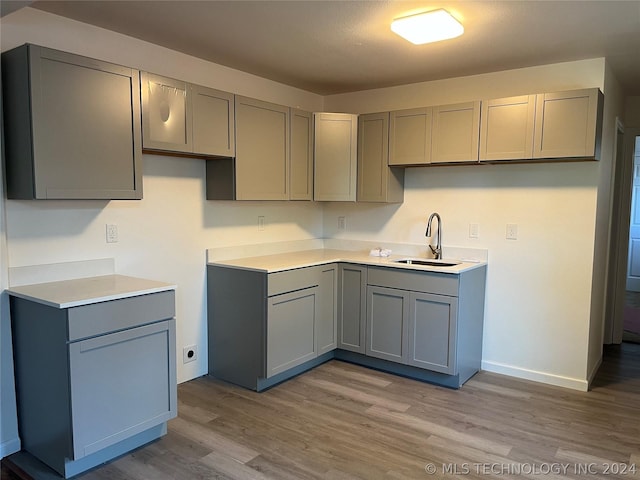 kitchen featuring gray cabinetry, sink, and hardwood / wood-style floors