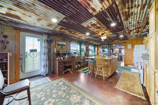 kitchen featuring wood walls, ceiling fan, a center island, and a kitchen breakfast bar