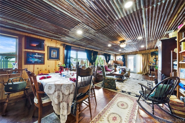 tiled dining space with wooden walls, ceiling fan, and a healthy amount of sunlight