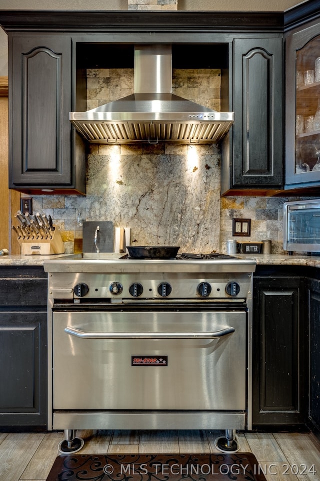 kitchen featuring backsplash, high end range oven, light hardwood / wood-style flooring, and wall chimney exhaust hood