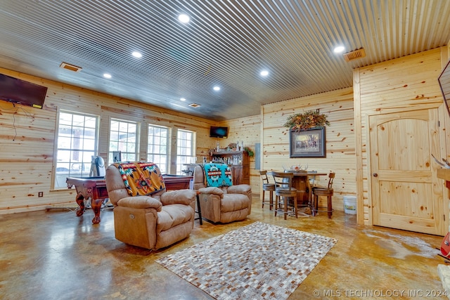 living room featuring concrete floors, wood walls, and pool table