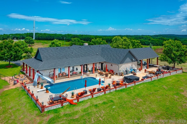 view of swimming pool with a yard, a water slide, and a patio area