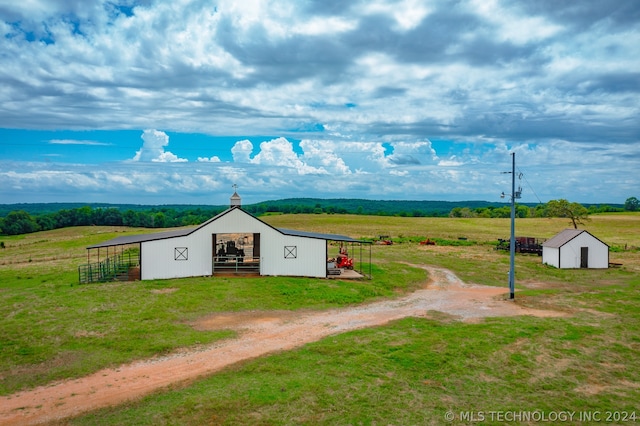 exterior space featuring an outdoor structure, a front yard, and a rural view