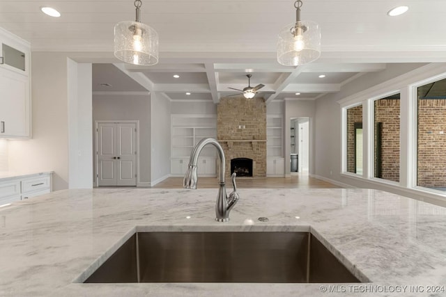 kitchen featuring a fireplace, decorative light fixtures, light stone countertops, and sink