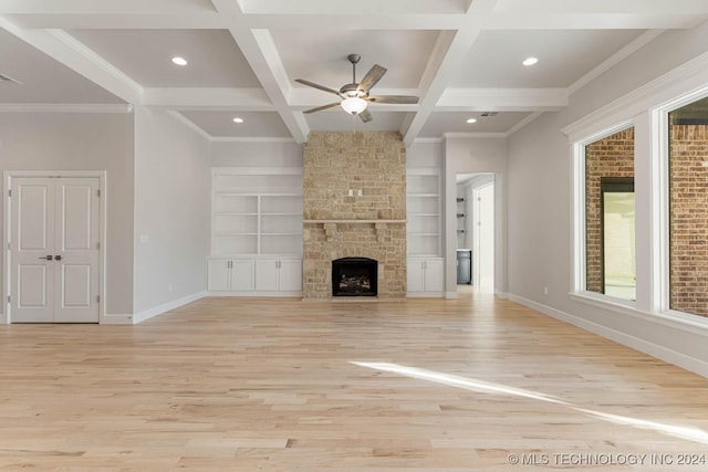 unfurnished living room with beam ceiling, a stone fireplace, light hardwood / wood-style floors, and coffered ceiling