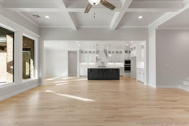 unfurnished living room featuring light hardwood / wood-style floors, sink, beam ceiling, and coffered ceiling