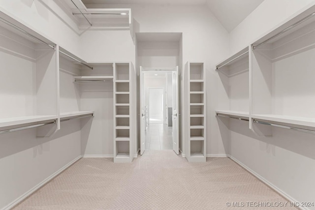 walk in closet featuring light carpet and vaulted ceiling