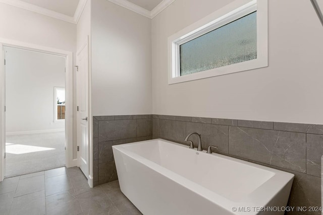 bathroom with tile patterned floors, a bathing tub, tile walls, and ornamental molding