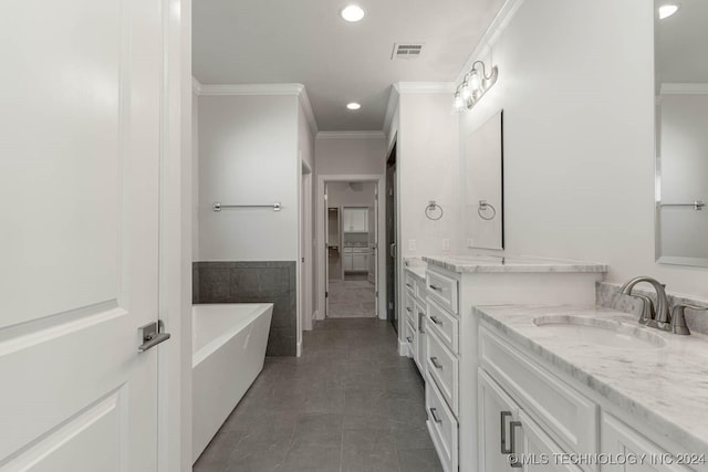 bathroom featuring tile patterned floors, vanity, crown molding, and a bathing tub