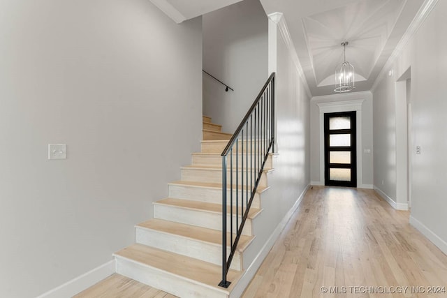 foyer entrance featuring a notable chandelier, light hardwood / wood-style floors, and ornamental molding