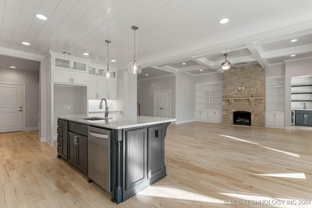 kitchen with built in shelves, a stone fireplace, white cabinetry, and a kitchen island with sink