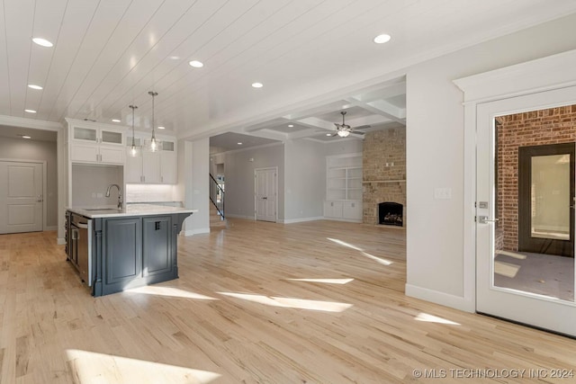 kitchen with white cabinets, pendant lighting, light wood-type flooring, and a fireplace