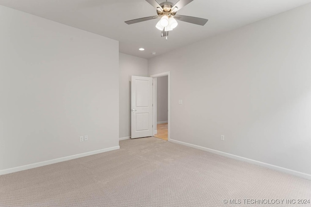 empty room featuring ceiling fan and light colored carpet