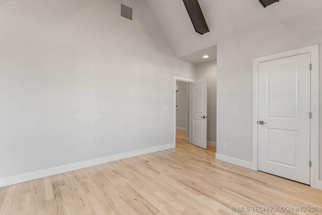 unfurnished bedroom with high vaulted ceiling and light wood-type flooring