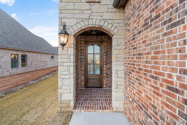 view of exterior entry featuring stone siding and brick siding