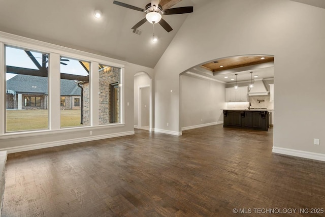 unfurnished living room with ceiling fan, dark hardwood / wood-style floors, sink, and high vaulted ceiling