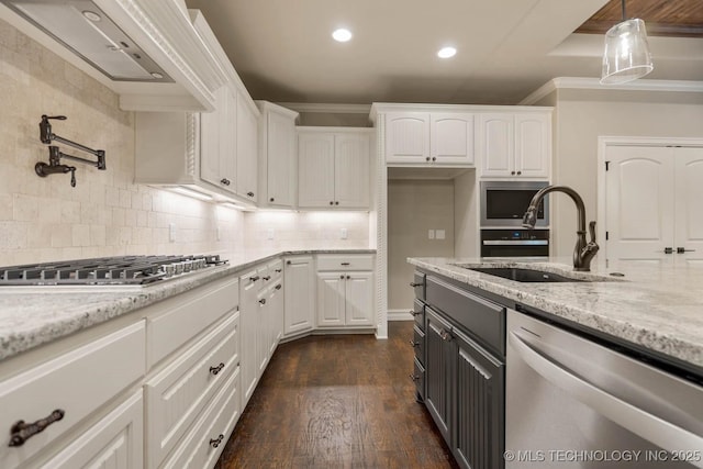 kitchen featuring light stone countertops, appliances with stainless steel finishes, sink, decorative light fixtures, and white cabinets