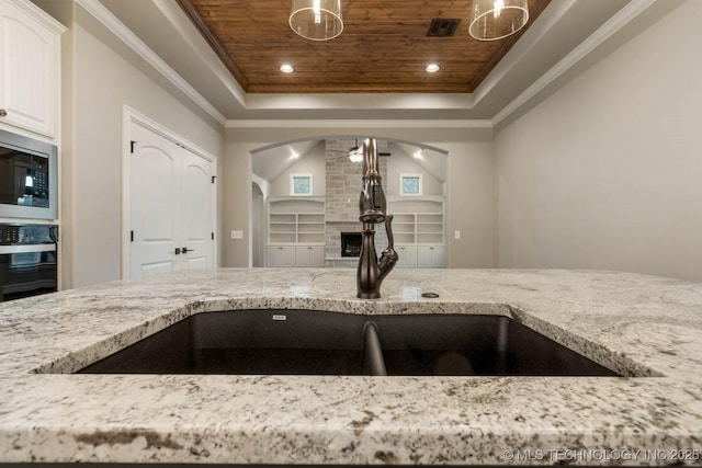 kitchen featuring black oven, white cabinetry, stainless steel microwave, and wooden ceiling