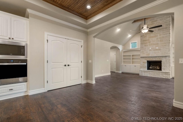 unfurnished living room featuring ceiling fan, wooden ceiling, a high ceiling, a stone fireplace, and dark hardwood / wood-style flooring