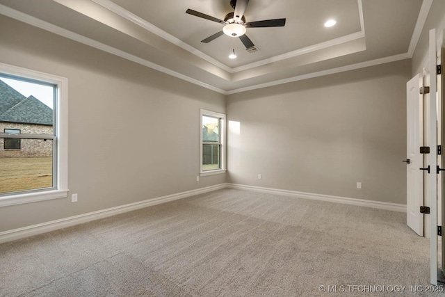 empty room featuring carpet flooring, a tray ceiling, ceiling fan, and ornamental molding