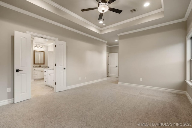 unfurnished bedroom featuring a tray ceiling, connected bathroom, crown molding, and ceiling fan