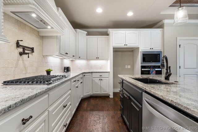 kitchen featuring appliances with stainless steel finishes, white cabinets, a sink, and light stone countertops