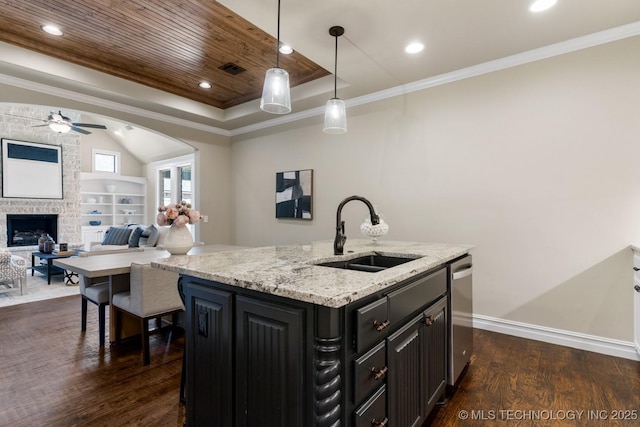 kitchen with dark wood-type flooring, a sink, open floor plan, hanging light fixtures, and a center island with sink