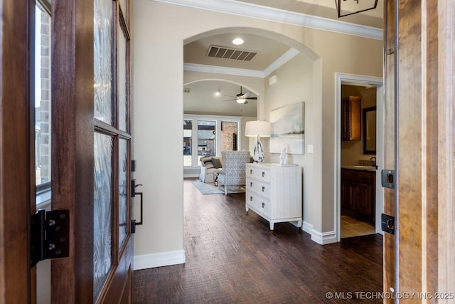 entrance foyer featuring baseboards, visible vents, arched walkways, dark wood-style floors, and ornamental molding