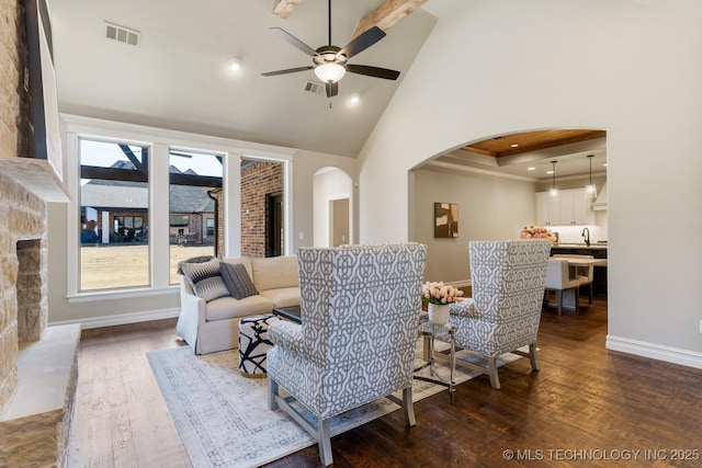 living room with dark wood-type flooring, arched walkways, visible vents, and high vaulted ceiling