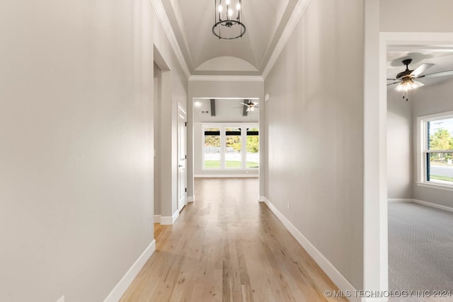 corridor featuring an inviting chandelier, crown molding, and light wood-type flooring