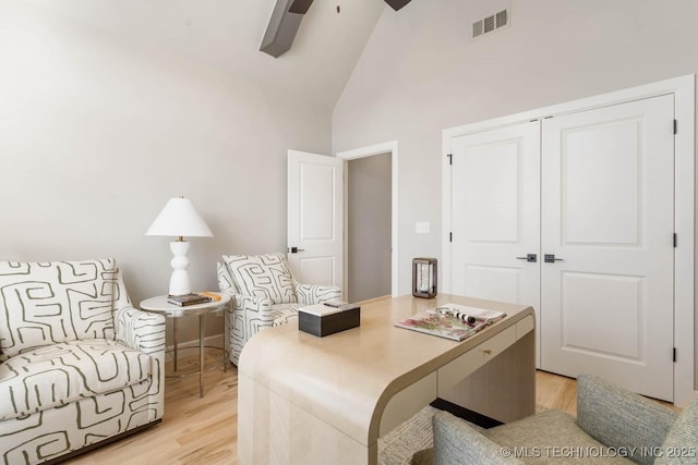 office area with light wood-style floors, visible vents, ceiling fan, and high vaulted ceiling