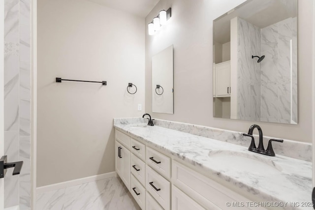 full bath featuring double vanity, marble finish floor, baseboards, and a sink