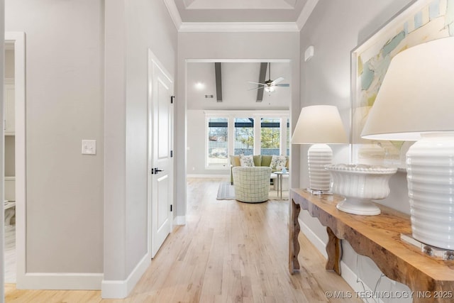 hall featuring light wood finished floors, ornamental molding, and baseboards