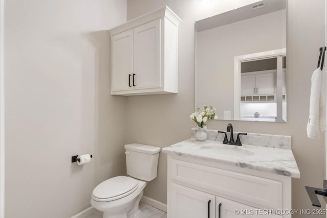 half bath with marble finish floor, visible vents, toilet, vanity, and baseboards