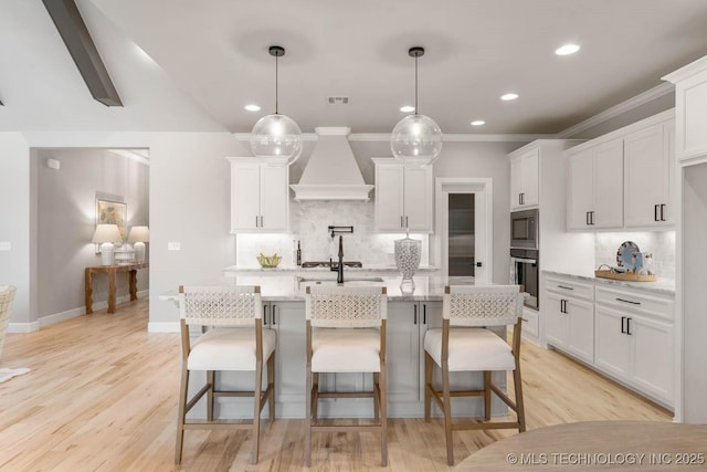 kitchen with light stone counters, premium range hood, white cabinetry, hanging light fixtures, and appliances with stainless steel finishes