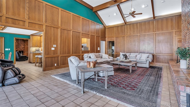 tiled living room with ceiling fan, beamed ceiling, brick wall, wooden walls, and high vaulted ceiling