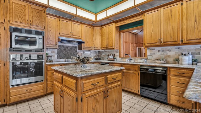 kitchen with a kitchen island, backsplash, light tile floors, sink, and appliances with stainless steel finishes