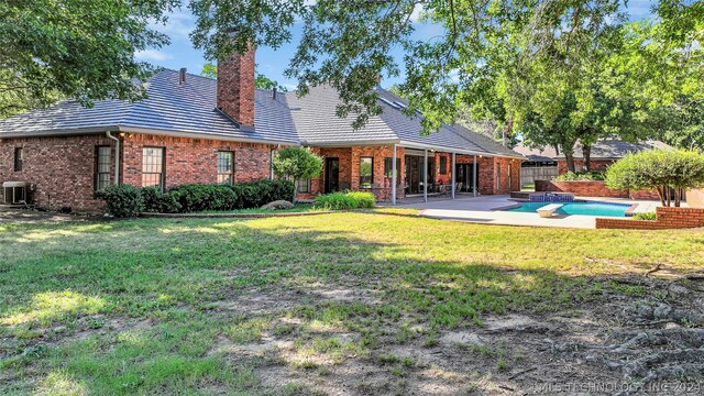 rear view of house with central AC, a patio area, and a yard