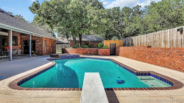 view of swimming pool with a patio area and a diving board