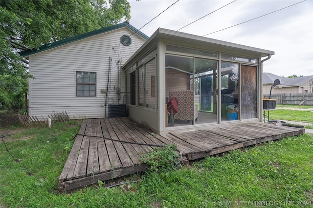 rear view of house with a lawn, a deck, and a sunroom