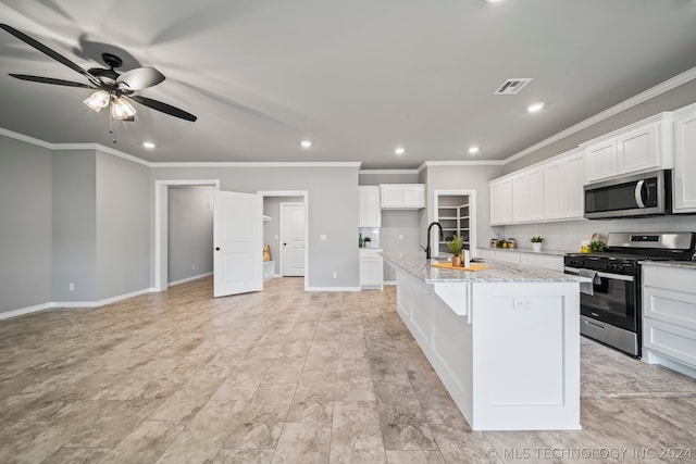 kitchen featuring light stone counters, a center island with sink, ceiling fan, white cabinetry, and appliances with stainless steel finishes