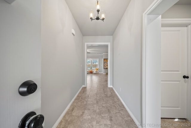 hallway featuring an inviting chandelier and light tile floors